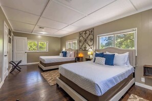 A bedroom with two beds, a large window, and a decorative wall piece. - Downtown Bliss: Hot Tub (Fredericksburg)