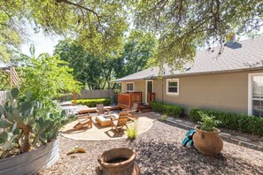 Una casa con patio, mobiliario exterior, un cactus y una maceta grande.