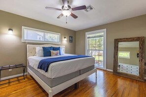 Un dormitorio con cama, ventilador de techo, ventana y puerta.