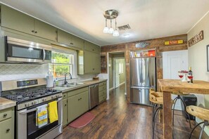 Una cocina con electrodomésticos de acero inoxidable, una mesa de comedor de madera y vistas al exterior.