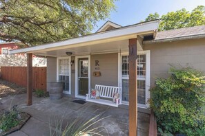 A house with a covered porch, a swing bench, and a mailbox. - Downtown Bliss: Hot Tub (Fredericksburg)