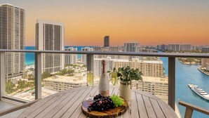 Ein Balkon mit einem Holztisch, einer Weinflasche und einem Blumentopf.