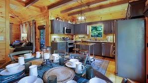 A wooden cabin interior with a dining area, kitchen, and living space. - Bentley's Retreat On Overlook (Blue Ridge)