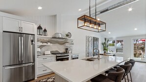 A modern kitchen with a large island, stainless steel appliances, and pendant lighting. - The Lofts of Brick and Mortar-City Loft |Stylish |Walk-Out Balcony |2 Kings |Parking for 2 |Downtown (Lake Geneva)