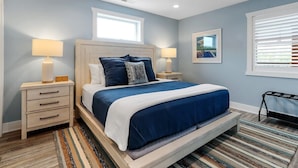 A bedroom with a bed, two bedside tables, a window, and a picture on the wall. - The Lofts of Brick and Mortar-Lake Loft |Luxury |Walk-Out Balcony |2 Kings |Parking for 2 |Downtown (Lake Geneva)