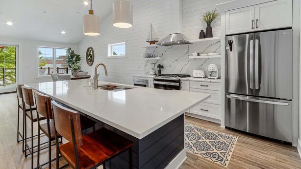 A modern kitchen with a large island, stainless steel appliances, and a marble backsplash. - The Lofts of Brick and Mortar-Lake Loft |Luxury |Walk-Out Balcony |2 Kings |Parking for 2 |Downtown (Lake Geneva)