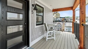 A wooden deck with a white railing, a door with a number '5', and a window with blinds. - The Lofts of Brick and Mortar-Lake Loft |Luxury |Walk-Out Balcony |2 Kings |Parking for 2 |Downtown (Lake Geneva)
