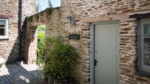 A stone building with a sign reading "GRANARY" and a door. There is a potted plant next to the door. - Granary Cottage -  a cottage that sleeps 2 guests  in 1 bedroom (Kingsbridge)