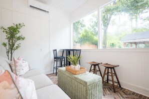 A bright room with a large window, a sofa, a small table, and a chair. - Historic Gem on Williams St. Centrally Located in Valdosta Georgia (Valdosta)