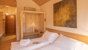 A bedroom with a wooden ceiling, a bed with white linens, a wooden wardrobe, and a large abstract painting on the wall. - B&B GIALLO - Felce Wellness Room (Pieve di Cadore)