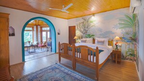 A bedroom with a wooden ceiling, a bed, a nightstand, a lamp, a wall mural, and a view of the outside. - Seclude Nahan Bantony Cottage (Paonta Sahib)