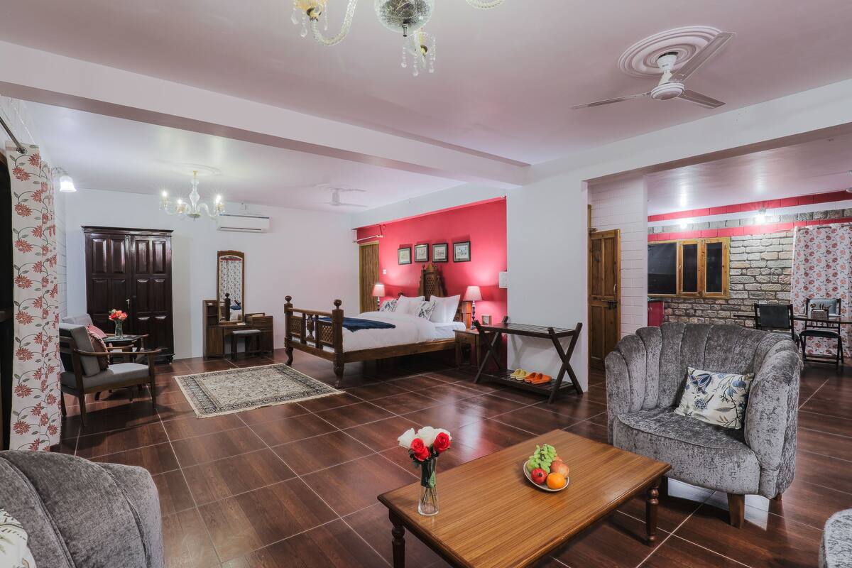 A well-lit room with a bed, a sofa, a dining table, and a chandelier.