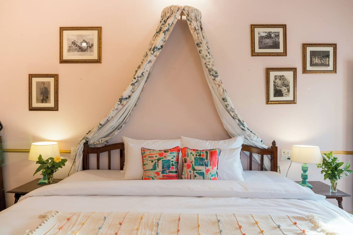 A bed with a canopy, two bedside tables with lamps, and framed pictures on the wall.