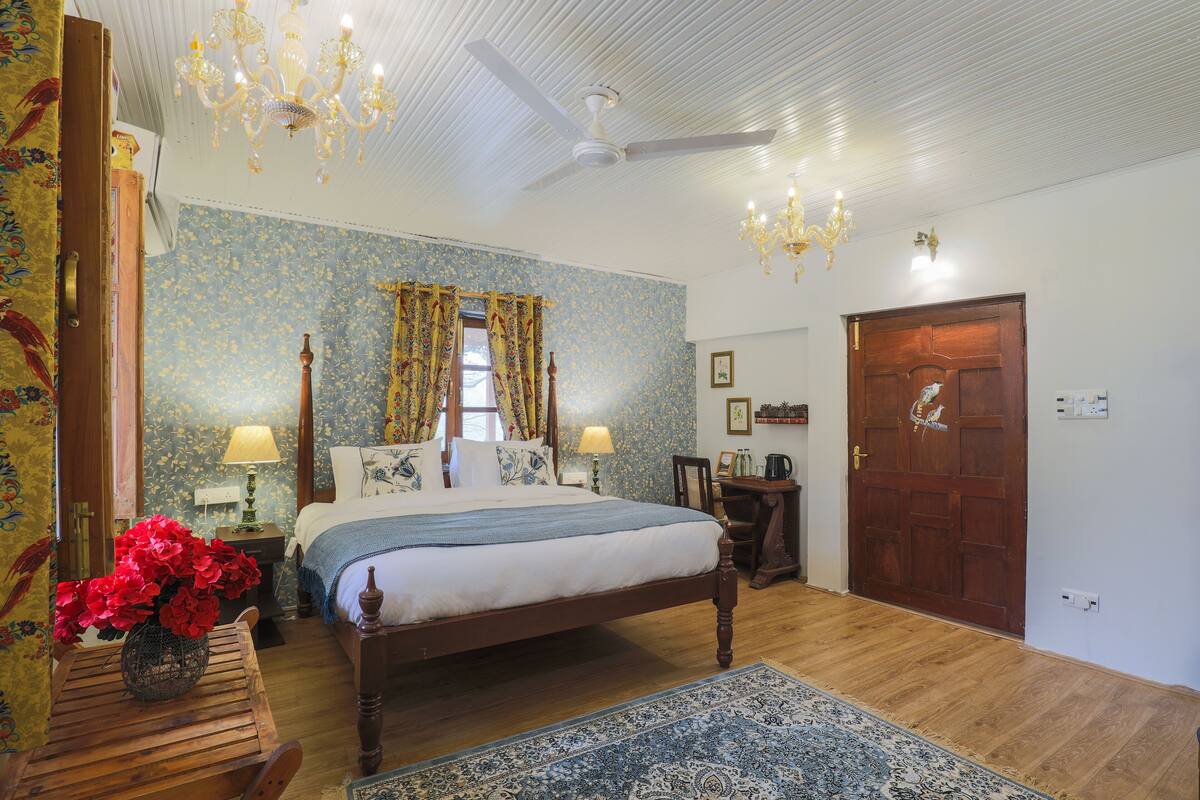 A bedroom with a wooden bed, a chandelier, a ceiling fan, and floral wallpaper.