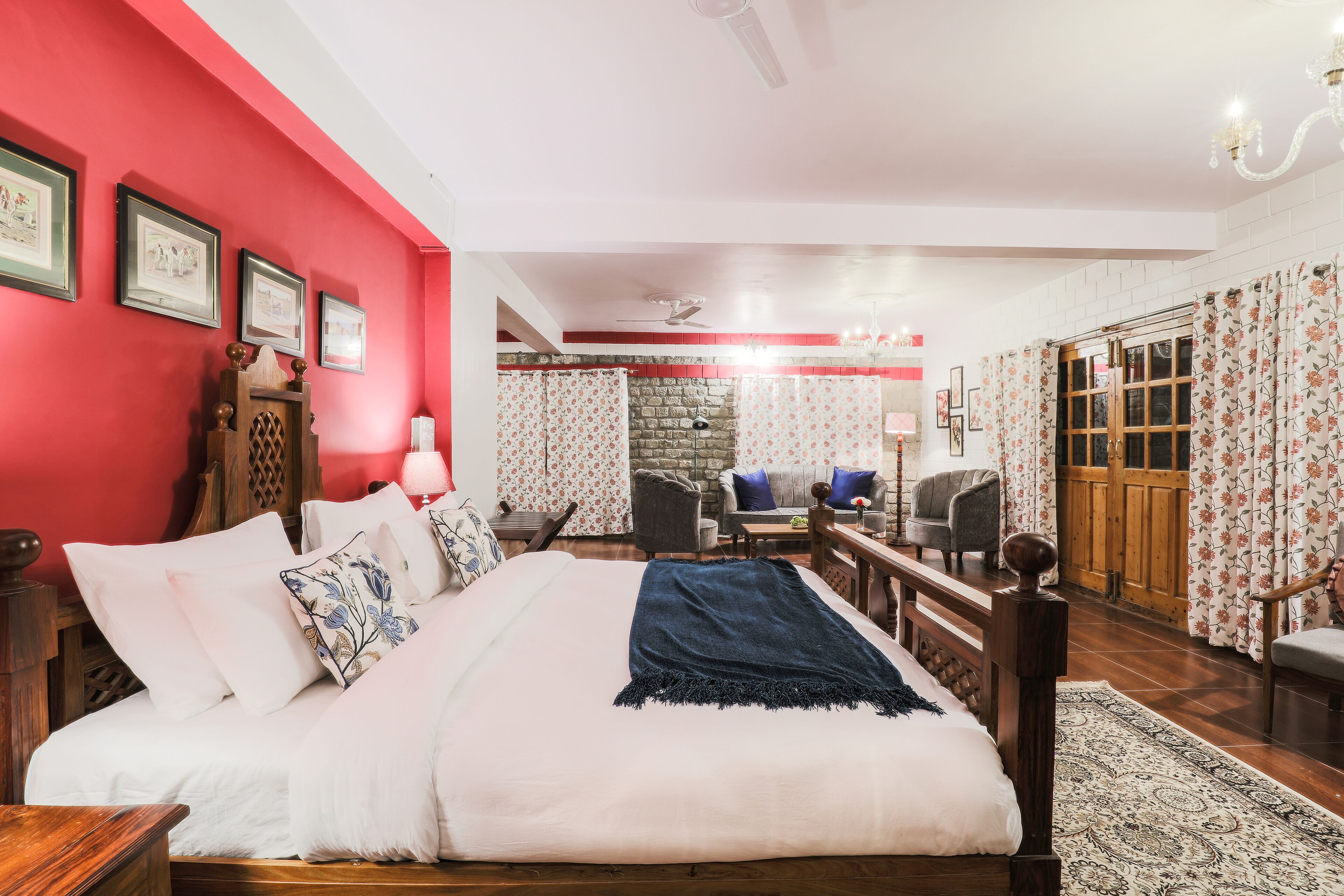 Un dormitorio con una cama grande, cabecera de madera, pared de acento roja y pared de piedra al fondo.
