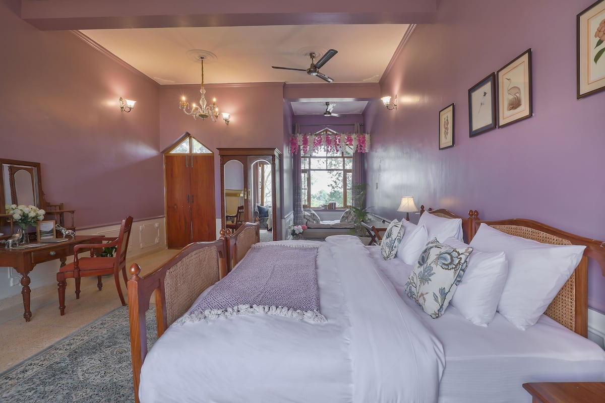 A bedroom with a large bed, wooden furniture, a desk, and a chandelier.