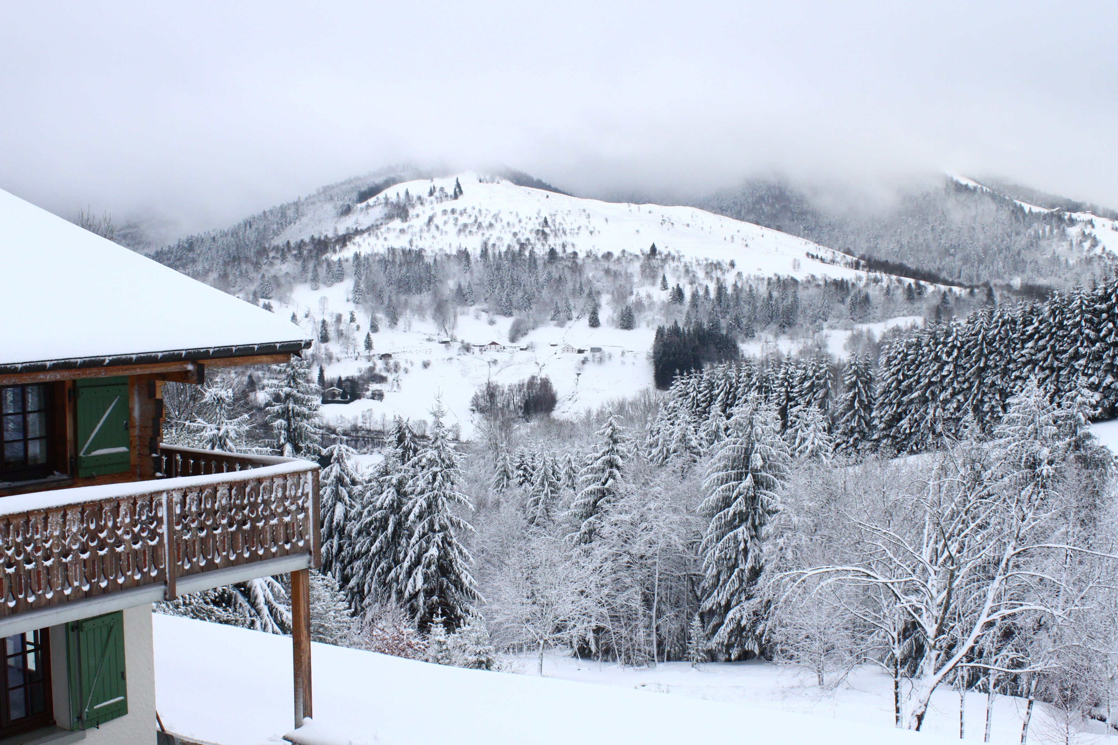 A snow-covered mountain landscape with a wooden building featuring a balcony.