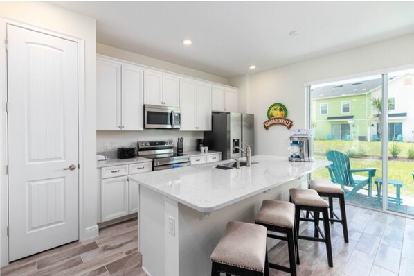 A modern kitchen with white cabinets, stainless steel appliances, and a large island with bar stools.