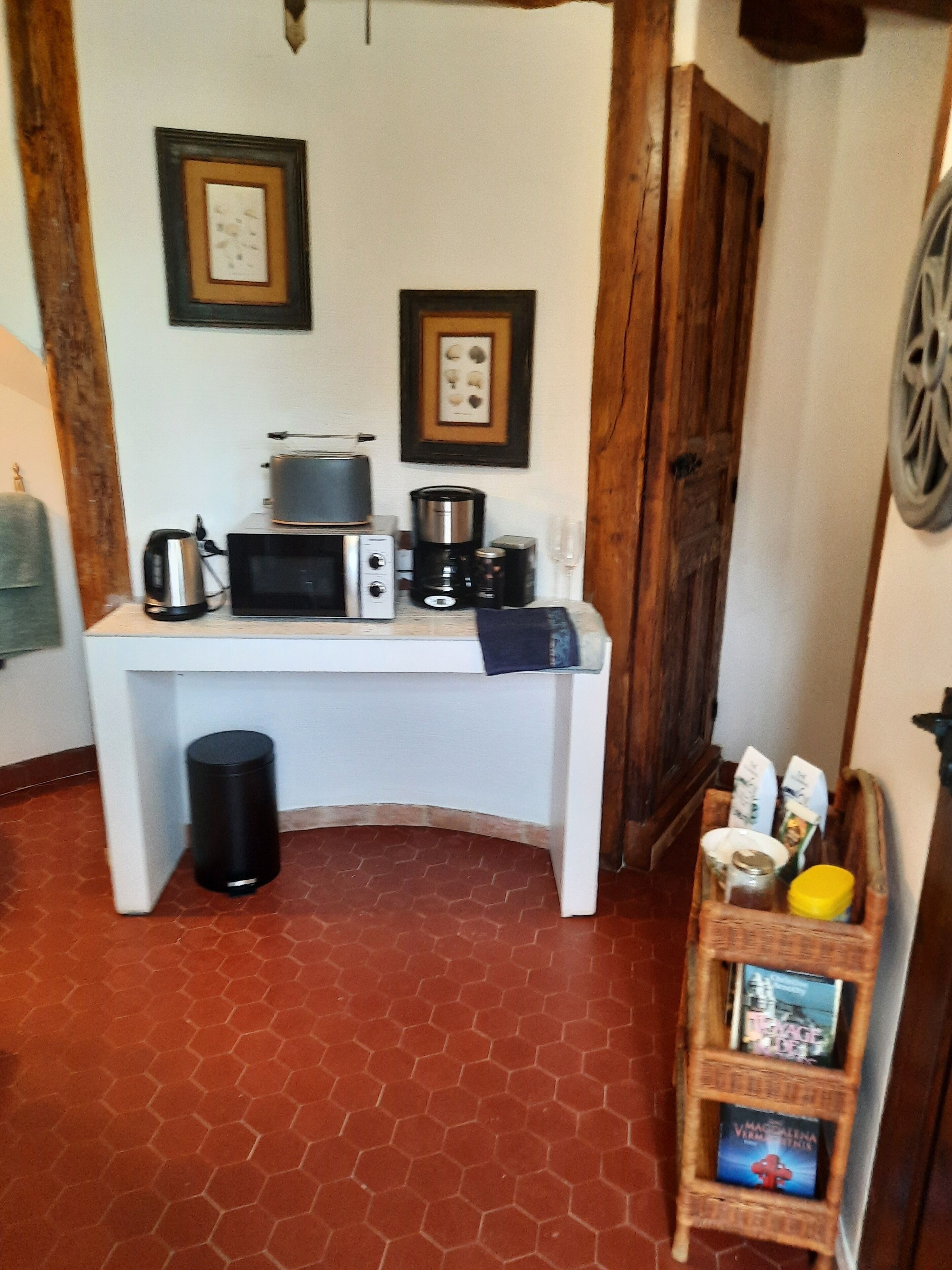 Een kleine keuken met een magnetron, broodrooster en koffiezetapparaat op een wit aanrecht.