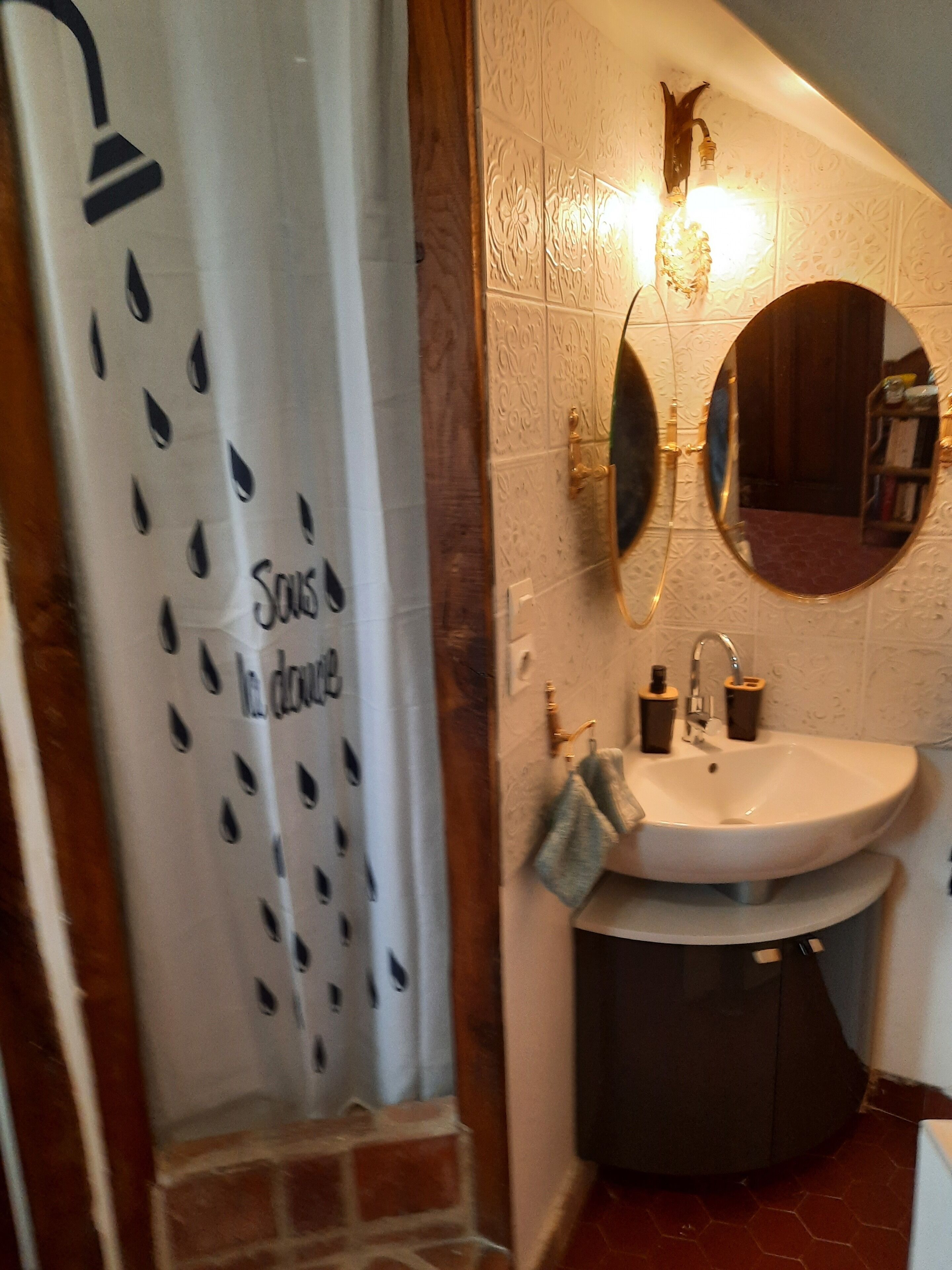 A bathroom with a shower curtain, a sink, a mirror, and a towel rack.