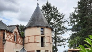 Un edificio tradicional con una torre cónica, fachada de ladrillo y un muro de piedra.