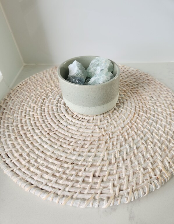 A woven placemat with a ceramic bowl containing crystals.
