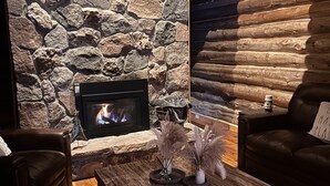 Un salon chaleureux avec une cheminée en pierre, des canapés en cuir et une table basse en bois.