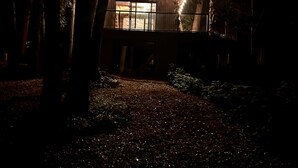 Une cabane en bois dotée d’un balcon, entourée d’arbres et illuminée par des guirlandes lumineuses.
