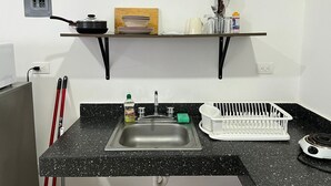 A kitchen with a black countertop, stainless steel sink, and a dish rack. - Studio on Cancun Downtown. Close to grocery stores, restaurants and bus stop. (Cancún)