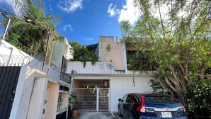 A residential area with a gated entrance, a parked car, and a building with a balcony. - Studio on Cancun Downtown. Close to grocery stores, restaurants and bus stop. (Cancún)