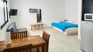 A compact room with a bed, a small table, a chair, a TV, a mirror, and a refrigerator. - Studio on Cancun Downtown. Close to grocery stores, restaurants and bus stop. (Cancún)