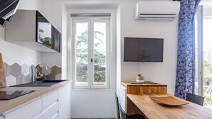 A compact kitchen with a wooden countertop, a built-in sink, and a window with a view of trees. - 2 Pieces Balcon et Climatisation 32m2 (Cannes)