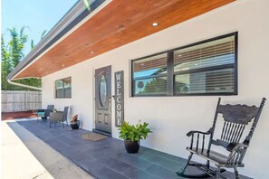 Welcome to a contemporary home with a cozy entrance featuring a front porch, bench, and potted plants.