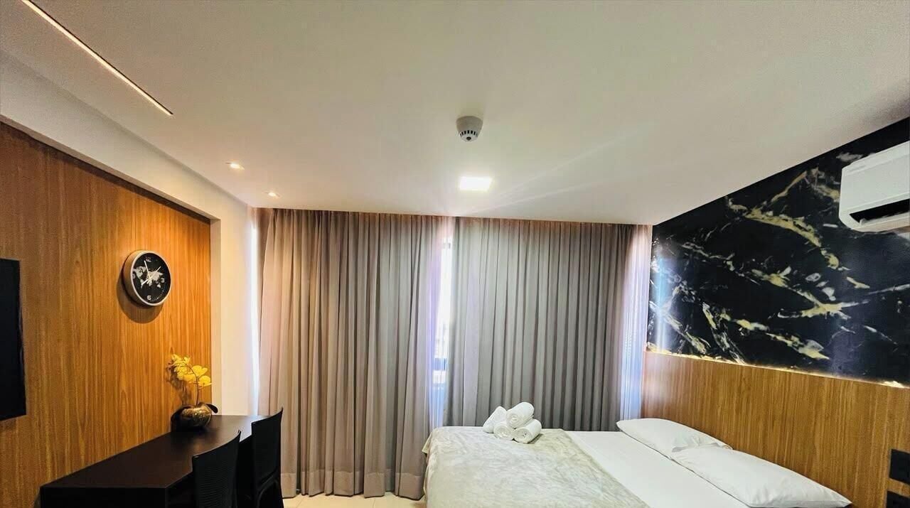Een hotelkamer met een bed, een bureau, een klok en een wandairconditioner.