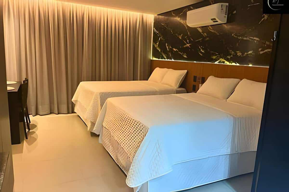 A hotel room with two beds, a dining area, and an air conditioning unit.