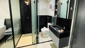 A modern bathroom with a glass shower enclosure, a white toilet, and a black vanity with a mirror. - LM HOSPEDAGENS - GET ONE (João Pessoa)
