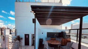 A rooftop terrace with a covered seating area, a small table, and a grill. - LM HOSPEDAGENS - GET ONE (João Pessoa)