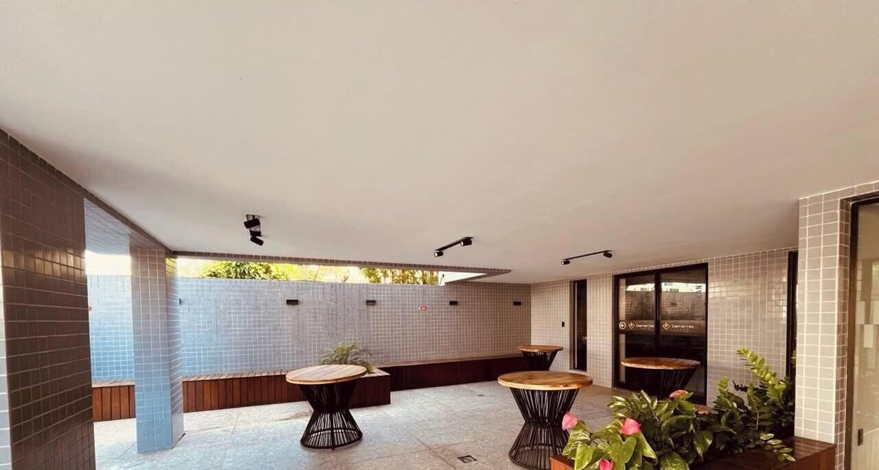 A modern outdoor patio with tiled walls, two round tables, and a bench.