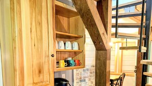 A kitchen with wooden cabinets, a granite countertop, a coffee maker, and a brick wall.