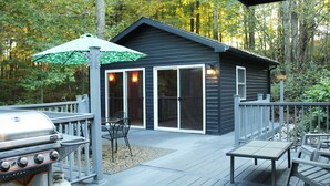 A deck with a grill, chairs, and a table.