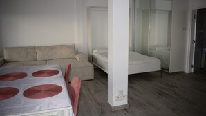 Un dormitorio moderno y minimalista con sofá, cama y mesa de comedor.