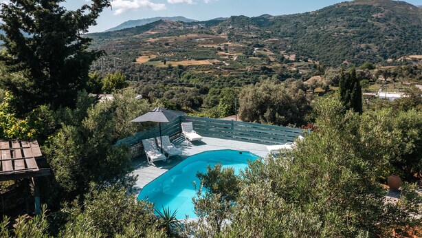 A pool area with lounge chairs and a pergola, surrounded by trees and overlooking a hilly landscape. - Rogalida,serene villa,pool,Near taverns (Lampini)