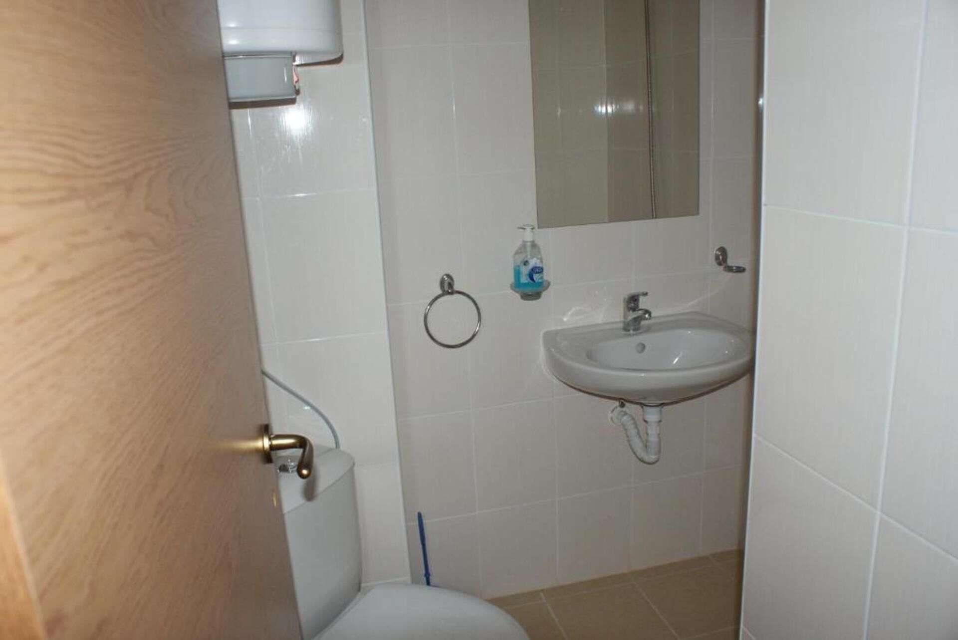 A bathroom with a toilet, sink, and mirror.