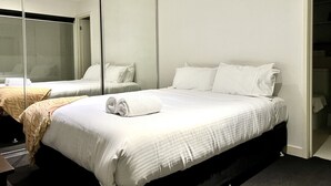 A hotel room with a large bed, a mirror, and a wardrobe.
