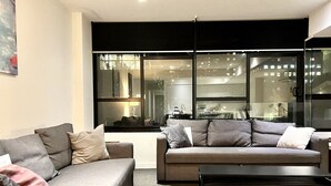 A modern living room with two sofas, a coffee table, and a large window with a city view.