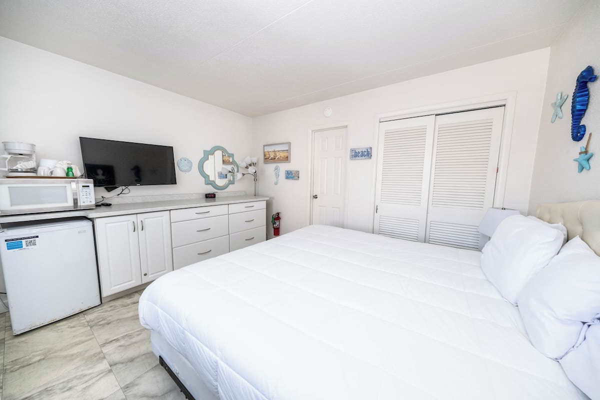 Une chambre avec un lit, une télévision, un four à micro-ondes et un petit réfrigérateur.