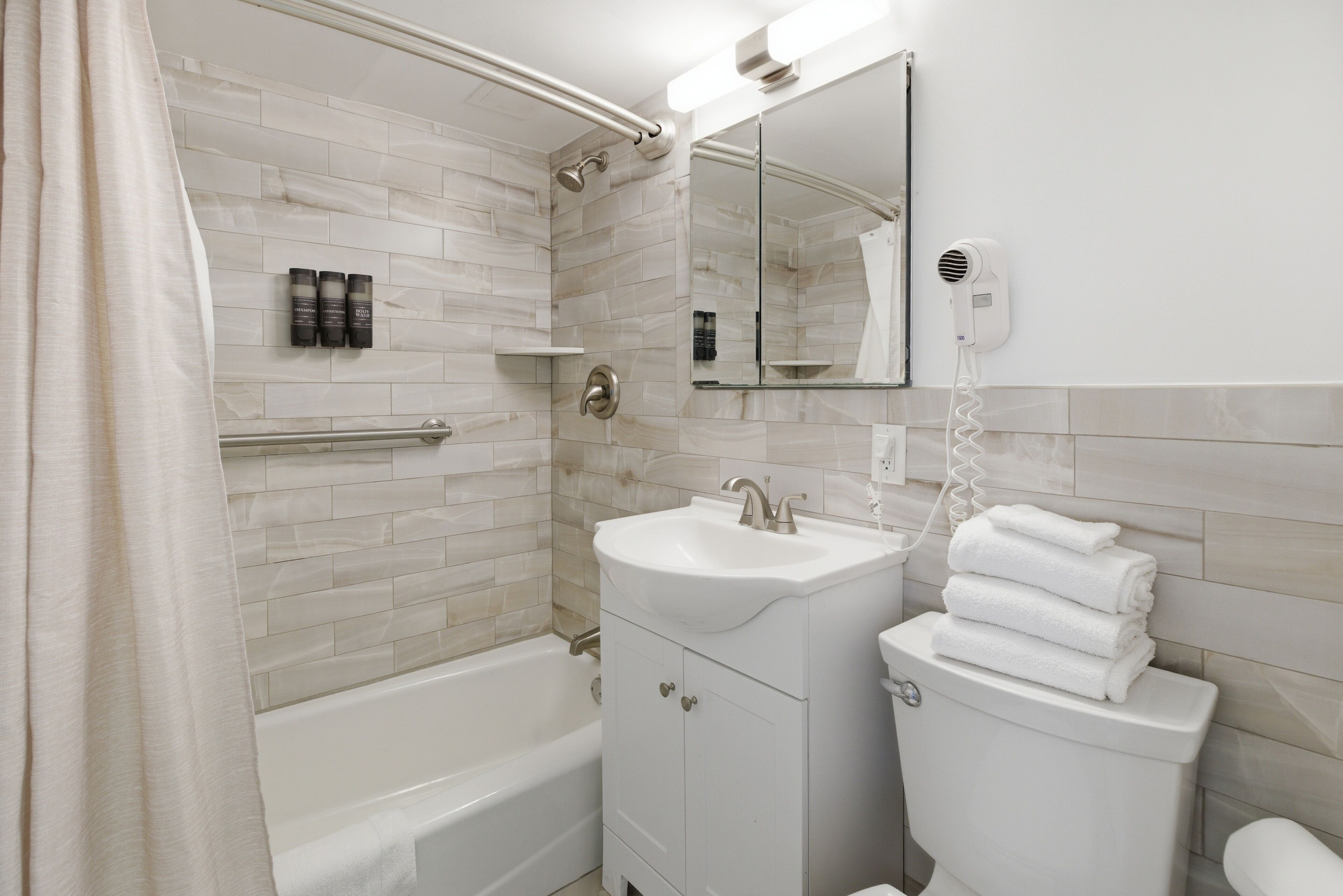 A bathroom with a bathtub, a sink, a toilet, a mirror, and a shower.