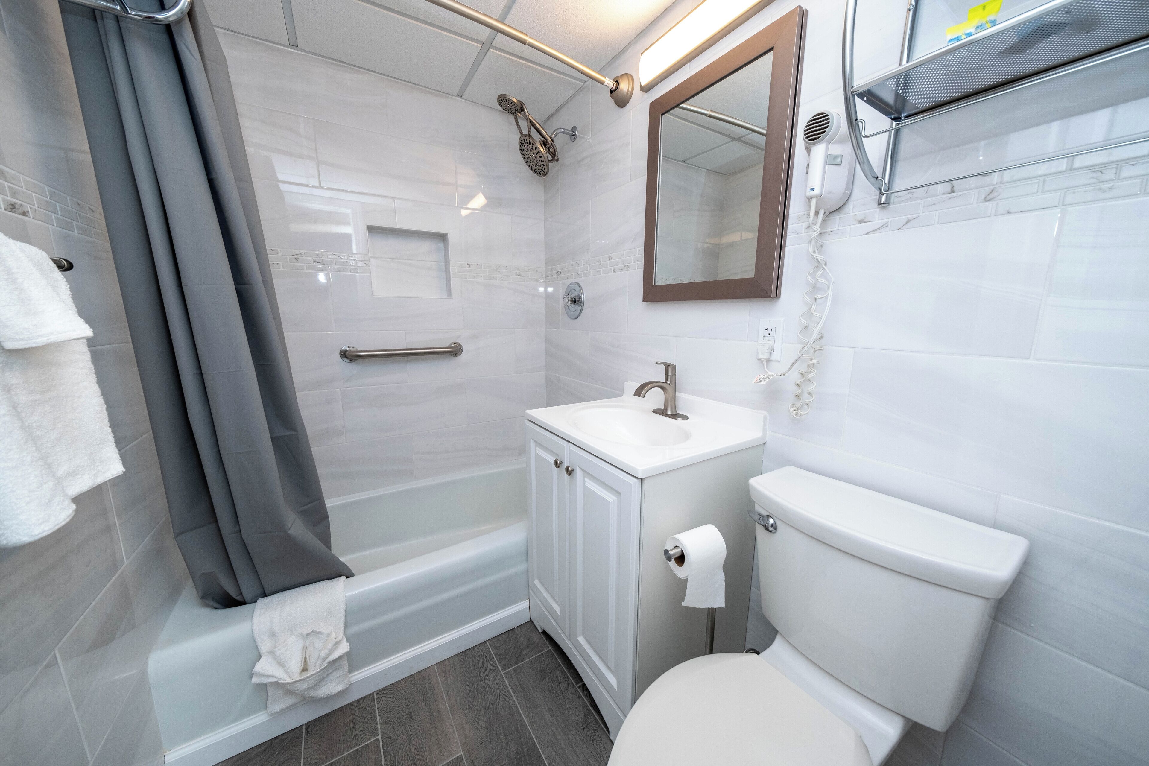 A modern bathroom with a shower, toilet, sink, and a mirror.