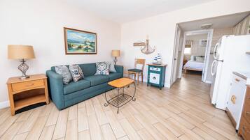 A compact living space with a sofa, a small table, a cabinet, and a refrigerator.