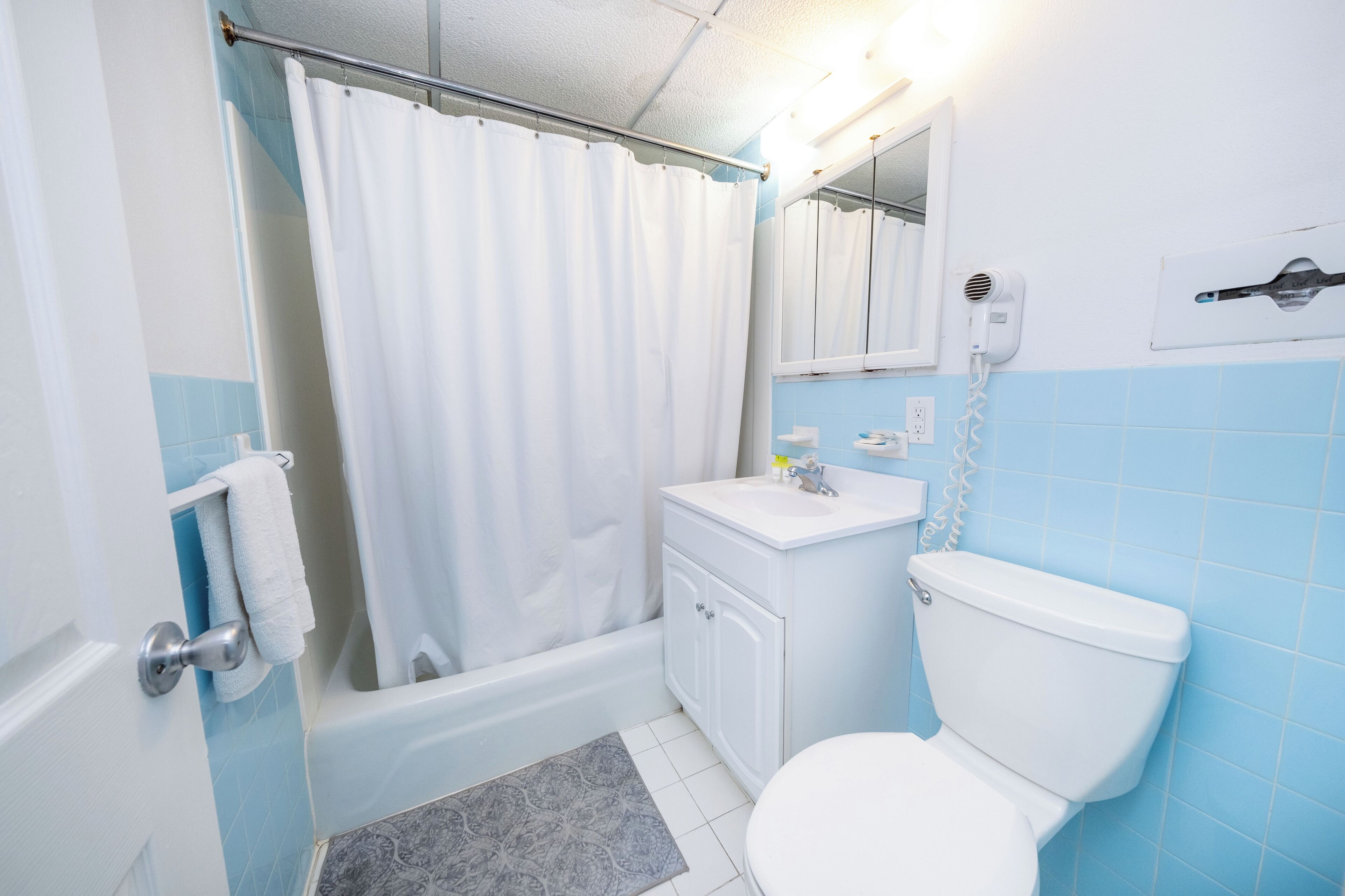 A bathroom with a bathtub, toilet, sink, and a shower curtain.
